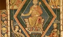 Gewebter Teppich, in desen Zentrum eine gekrönte sitzende Figur mit Zepter auf einem Thron zu sehen ist. Ringsum gruppieren sich vier weitere Figuren, Inschriftenbänder und Ornamente.
