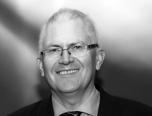 A black-and-white portrait photograph of a man wearing glasses