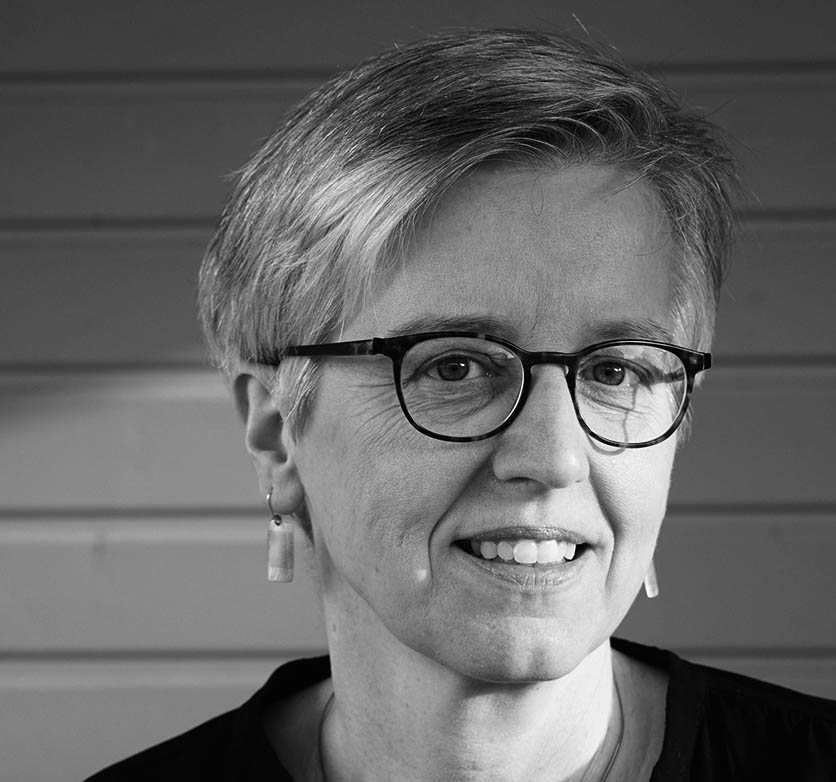 Black-and-white portrait photograph of a smiling woman wearing glasses